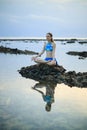 Young woman, meditating, practicing yoga and pranayama at the beach. Sunset yoga practice. Hands in gyan mudra. Water reflection. Royalty Free Stock Photo