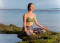 Young woman, meditating, practicing yoga and pranayama at the beach. Sunset yoga practice. Lotus pose. Hands in gyan mudra. Royalty Free Stock Photo