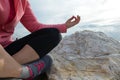 young woman meditation in a yoga pose at the beach. girl in lotus position on an empty stone seashore. takes yoga, sports,