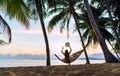 Young woman meeting sunrise sitting in hammock on the sand beach under the palm trees Royalty Free Stock Photo