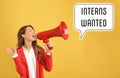 Young woman with megaphone and text INTERNS WANTED on background Royalty Free Stock Photo