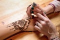 Young woman mehendi artist painting henna on the hand