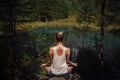 Young woman with mehendi on her back meditating near blue mountain lake