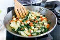 Young woman mixing chards, potatoes, red pepper and eggs into the pan. Royalty Free Stock Photo