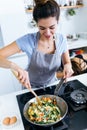 Young woman mixing chards, potatoes, red pepper and eggs into the pan. Royalty Free Stock Photo