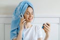 Young woman with mobile phone hold a credit card in hand sits in bed Royalty Free Stock Photo