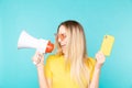 Young woman with mobile phone and megaphone on color background