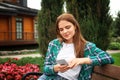 Young woman with mobile phone resting on wooden bench in park Royalty Free Stock Photo