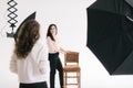 Young woman model posing with chair in photo studio for female photographer. Royalty Free Stock Photo