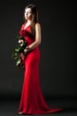 Young woman model in red dress standing and holding bouquet of red roses Royalty Free Stock Photo