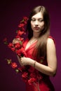 Young woman model in red dress standing and holding branch with flowers Royalty Free Stock Photo