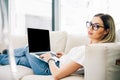 Young woman model sitting on a sofa using a laptop Royalty Free Stock Photo