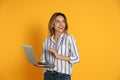 Young woman with modern laptop on yellow