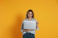 Woman with modern laptop on yellow background