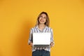 Young woman with modern laptop on yellow