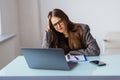 Young attractive woman at modern office desk, working on laptop, massaging temples to forget about constant headaches, noisy loud Royalty Free Stock Photo