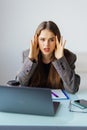 Young attractive woman at modern office desk, working on laptop, massaging temples to forget about constant headaches, noisy loud Royalty Free Stock Photo