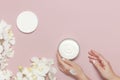 Young woman moisturizes her hand with cosmetic cream lotion opened container with cream body milk White Phalaenopsis orchid Royalty Free Stock Photo
