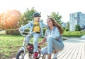 Young woman mom teaches child ride bicycle, little boy son. Rest on weekend in fall in park. Everyday warm clothes Royalty Free Stock Photo