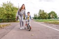 Young woman mom teaches child ride bicycle, little boy son. Rest on weekend in fall in park. Everyday warm clothes Royalty Free Stock Photo