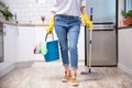 Young woman with mop and detergents in kitchen, closeup. Cleaning service Royalty Free Stock Photo