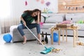 Young woman with mop suffering from hangover in room after party Royalty Free Stock Photo