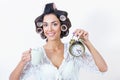 Young woman morning rush with coffee, clock and hair curlers