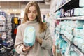 Young woman mother chooses diapers at supermarket in shop mall. Hygiene products for children. Royalty Free Stock Photo