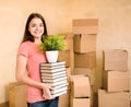 Young woman moving house to college, holding pile books and plan