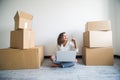 Young woman moving in a new flat, sitting on the floor and surfing the web on a tablet computer and have new decorating ideas Royalty Free Stock Photo