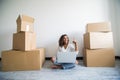 Young woman moving in a new flat, sitting on the floor and surfing the web on a tablet computer and have new decorating ideas Royalty Free Stock Photo