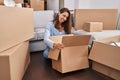 Young woman moving to a new home looking inside cardboard box sticking tongue out happy with funny expression Royalty Free Stock Photo