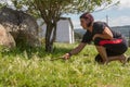 Young woman mowing lawn grass with ground sickle with leaves of grass moving up and down Royalty Free Stock Photo