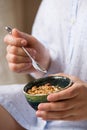 Young woman with muesli bowl. Girl eating breakfast cereals with nuts, pumpkin seeds, oats and yogurt in bowl. Royalty Free Stock Photo