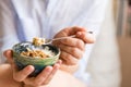 Young woman with muesli bowl. Girl eating breakfast cereals with nuts, pumpkin seeds, oats and yogurt in bowl.