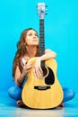 Young woman musician with guitar sitting on a floor Royalty Free Stock Photo