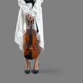 Young woman musician holding a violin in her lowered hands at her feet isolated on gray Royalty Free Stock Photo