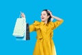 Young woman in a mustard dress holding shopping bags and looking proud Royalty Free Stock Photo