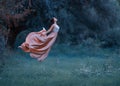 A young woman, a mysterious witch is floating in the air like a butterfly. A luxurious, long dress flutters in the wind Royalty Free Stock Photo