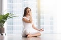 Young woman in nadi shodhana pranayam pose against floor window Royalty Free Stock Photo