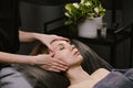 Young woman naping during face massage at asian beauty clinic. Side view