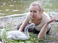 The young woman near a baby bird of a swan on the bank of the lake Royalty Free Stock Photo