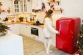 Young woman near red fridge in christmas decorated kitchen Royalty Free Stock Photo