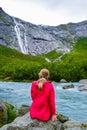 The young woman near the river which is located near path to the Briksdalsbreen Briksdal glacier. Norway Royalty Free Stock Photo