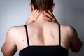 Young woman with neck pain on gray background