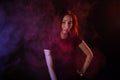 Young woman in neon light and smoke of e-cigarettes or vape on black background
