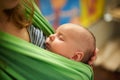 Young woman with newborn infant baby in a sling with a blurred background at home Royalty Free Stock Photo