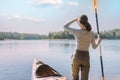 Woman stands next to a kayak outdoor.