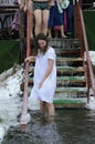 Young woman in a nightshirt going down steps into icy water before baptizing, people legs on a background. Feast Royalty Free Stock Photo