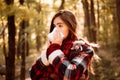 Young woman with nose wiper near autumn tree. Sick girl with runny nose and fever. Showing sick woman sneezing at autumn